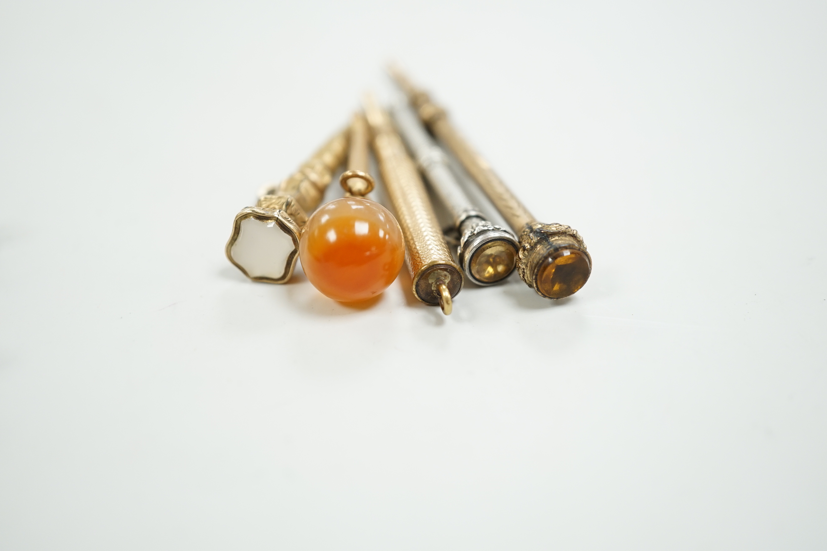 Four assorted early 20th century yellow or white metal overlaid propelling pencils, an agate set button hook, a two colour paste brooch and a Victorian enamelled mourning brooch, with plaited hair.